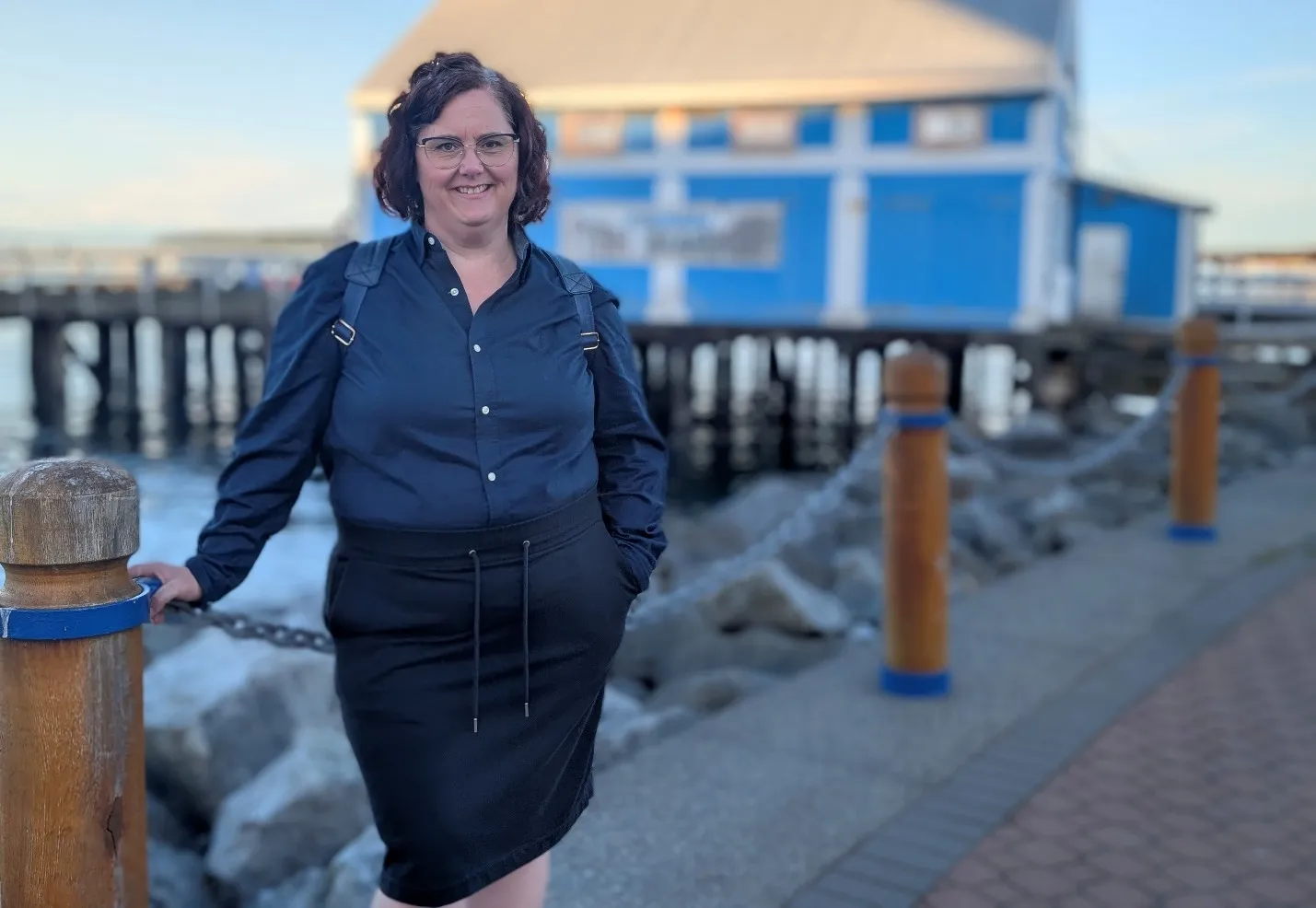 Erin standing at the Sidney waterfront, next to the Fish Market building on the pier